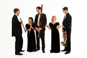 Atéa Quintet with a white background standind with their instruments