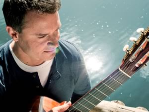 Craig Ogden with guitar near water